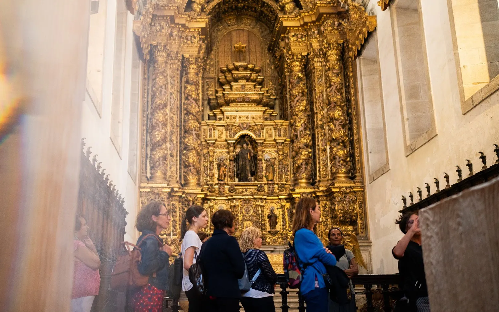 Tourists with guide in Monastery of São Bento da Vitória, Porto, admiring ornate altar.