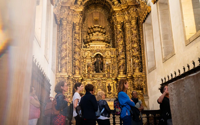 Tourists with guide in Monastery of São Bento da Vitória, Porto, admiring ornate altar.