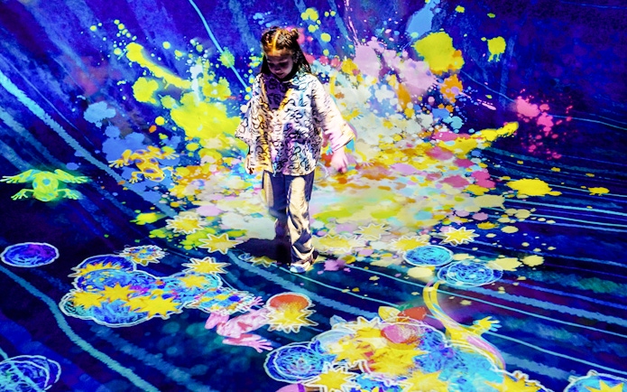 Child interacting with colorful digital art installation at Team Lab Abu Dhabi.