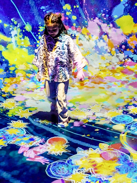 Child interacting with colorful digital art installation at Team Lab Abu Dhabi.