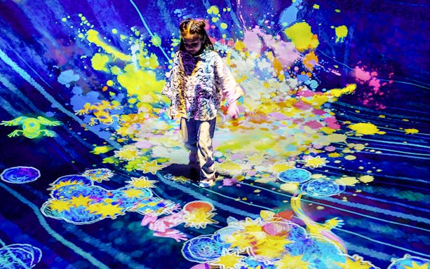 Child interacting with colorful digital art installation at Team Lab Abu Dhabi.