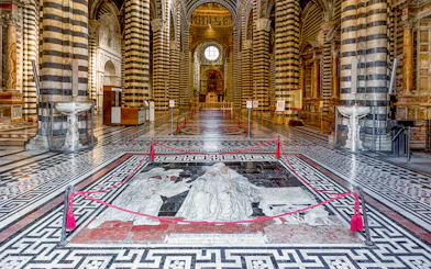 Siena Cathedral interior with intricate marble floor design and striped columns.