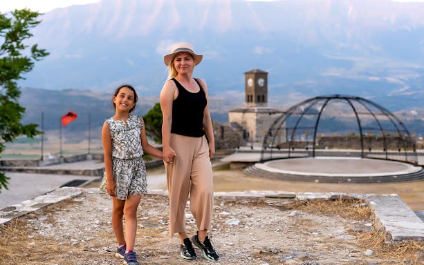 Guests exploring Gjirokaster Castle with clock tower in the background.