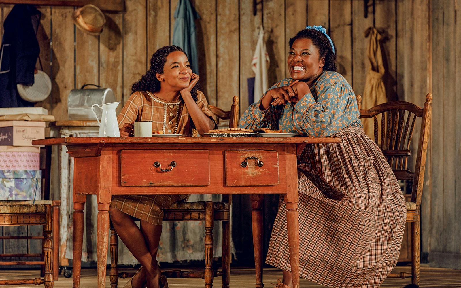 Two actors smiling at a wooden table in a scene from "Purlie Victorious: A Non-Confederate Romp.