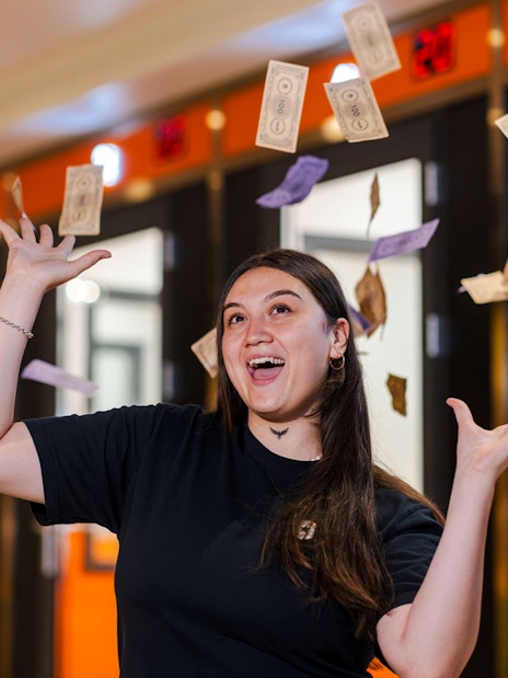 Person enjoying Monopoly Dreams Melbourne with play money in the air.