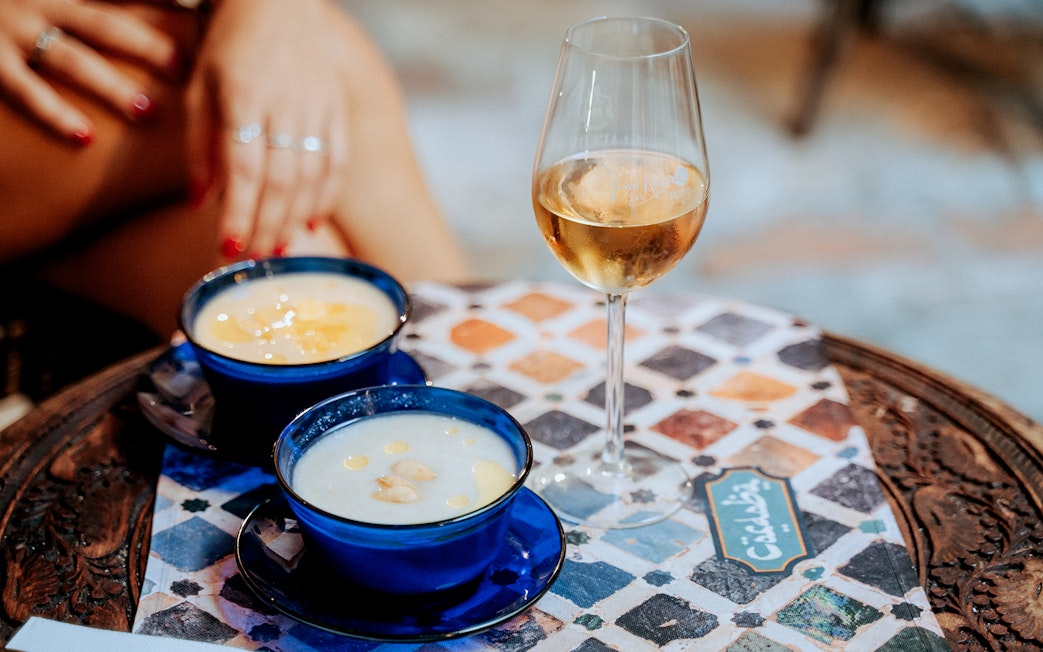 Two blue cups of soup and a glass of wine on a patterned table at Tablao Arab Baths.