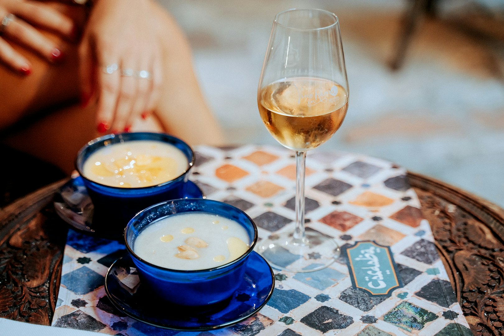 Two blue cups of soup and a glass of wine on a patterned table at Tablao Arab Baths.