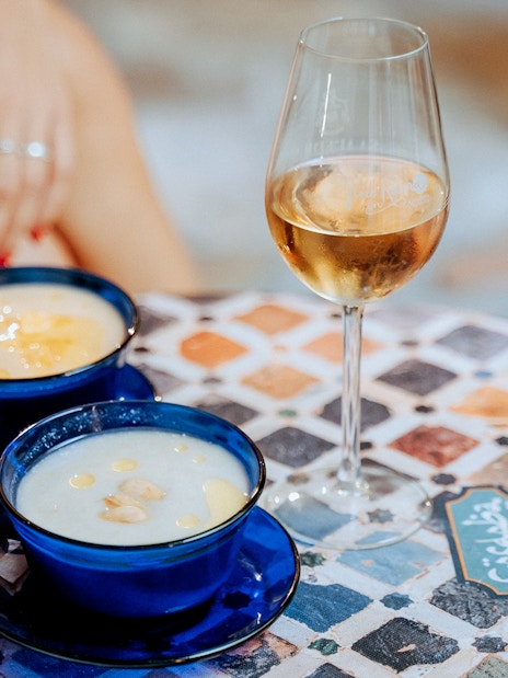 Two blue cups of soup and a glass of wine on a patterned table at Tablao Arab Baths.