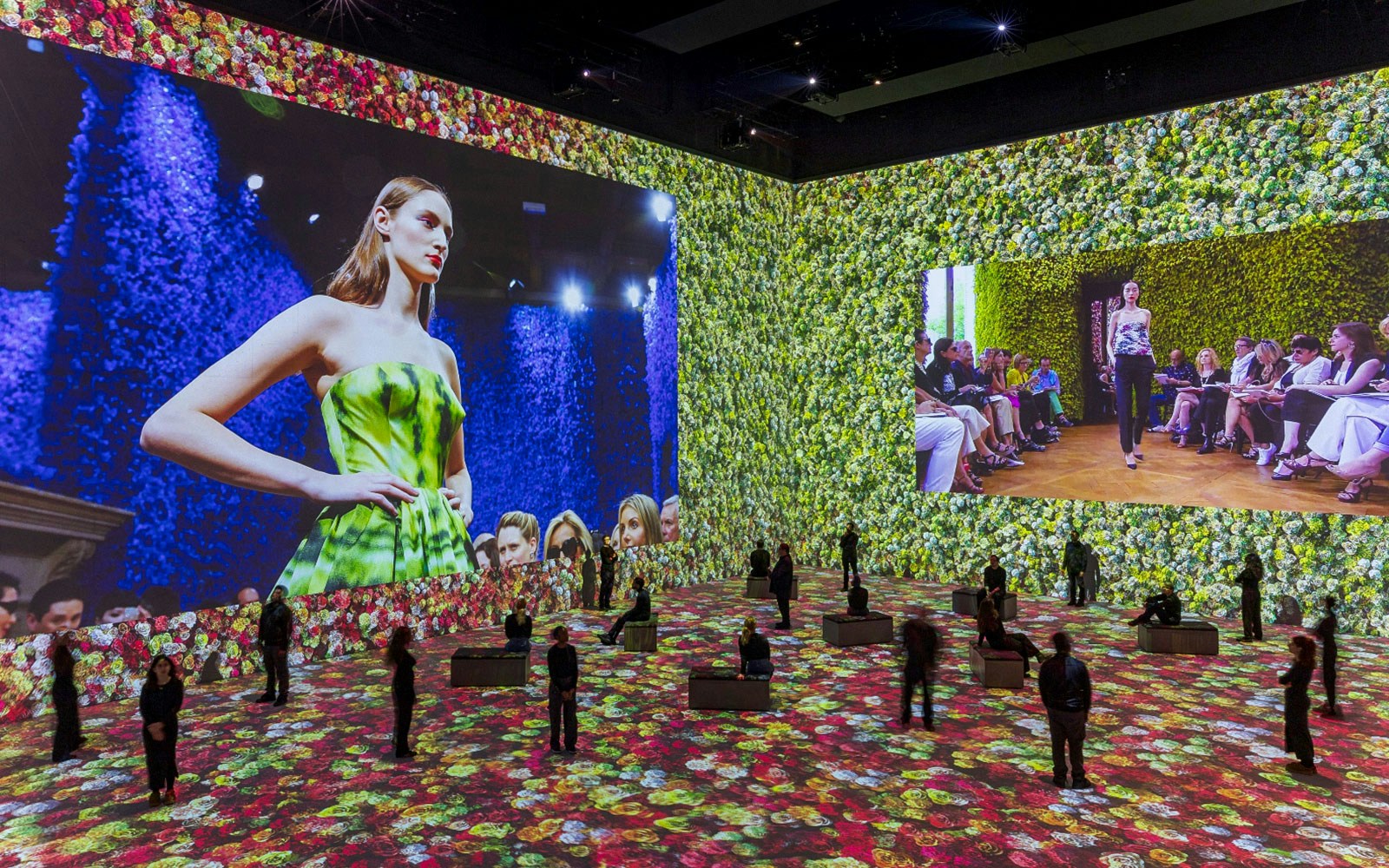 Fashion show projection with models on floral backdrop at Vogue: Inventing the Runway event.