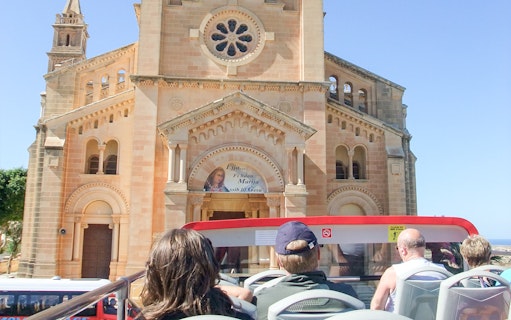 Open-top bus tour passing Ta' Pinu Basilica in Gozo.
