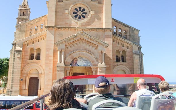 Open-top bus tour passing Ta' Pinu Basilica in Gozo.