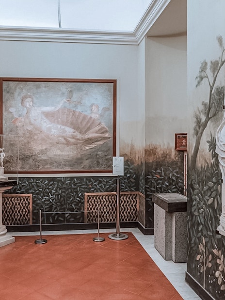 National Archaeological Museum Naples interior with classical sculptures and fresco.