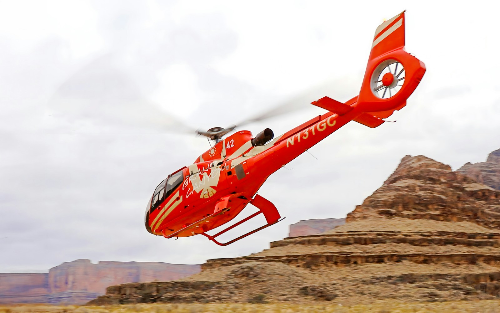 Helicopter flying over Grand Canyon West Rim with view of Colorado River, part of 15-min tour with floor landing and boat ride.