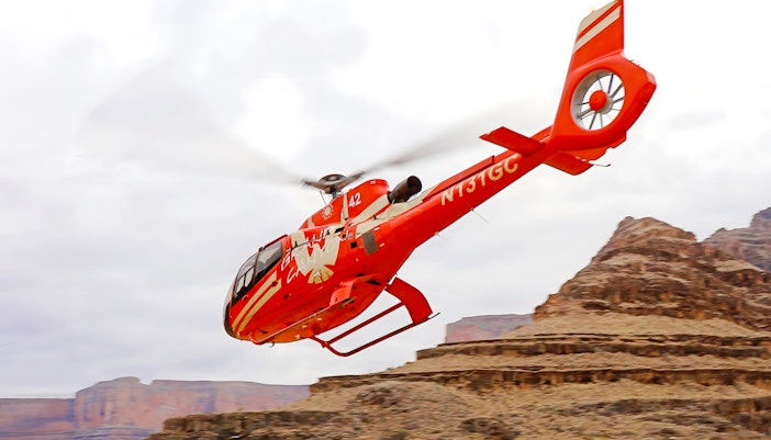 Helicopter flying over Grand Canyon West Rim with view of Colorado River, part of 15-min tour with floor landing and boat ride.