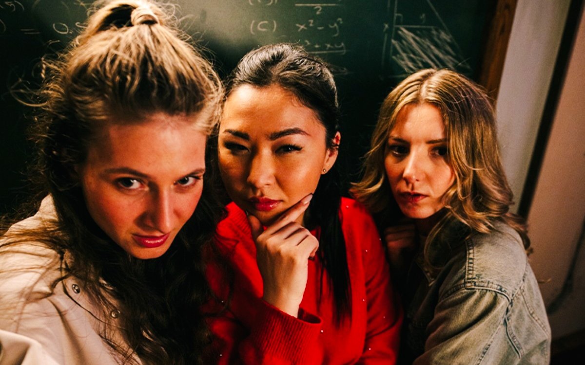 Three people posing in front of a chalkboard at Prison Island Brisbane.