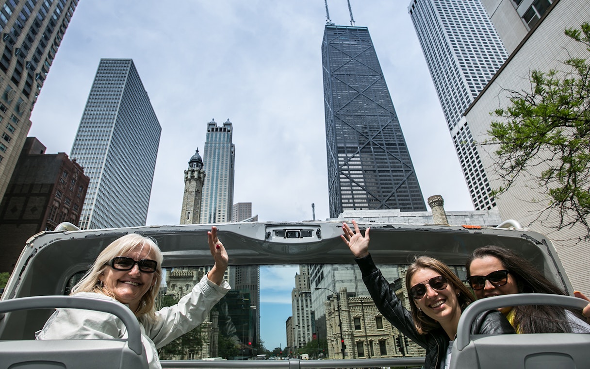 Tourists on an open-top bus enjoying the Chicago skyline during a Hop-On-Hop-Off tour.