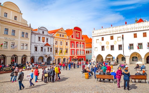 Cesky Krumlov main square with colorful historic buildings and tourists exploring.