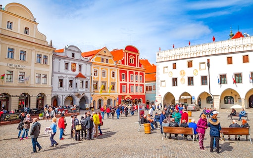 Cesky Krumlov main square with colorful historic buildings and tourists exploring.