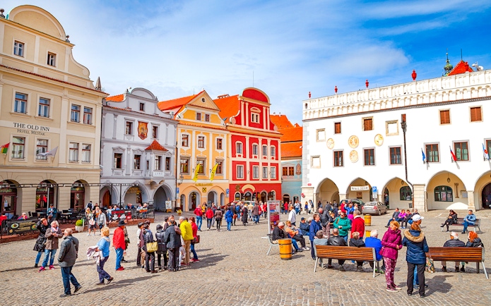 Cesky Krumlov main square with colorful historic buildings and tourists exploring.