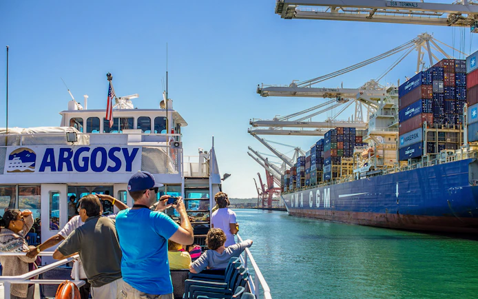 Tourists on Argosy cruise near container ship at Seattle port, part of Seattle CityPASS® experience.