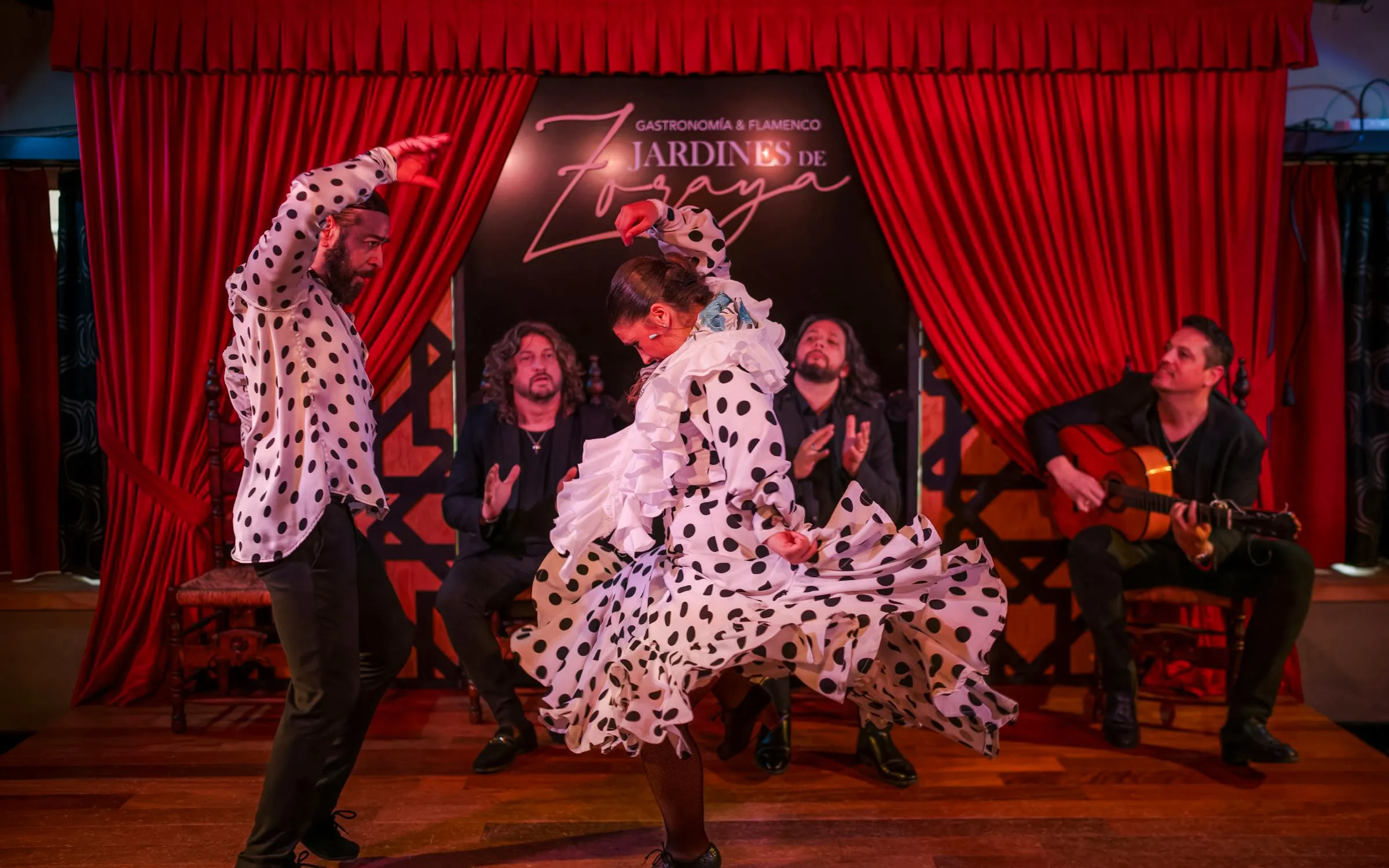 Flamenco dancers performing at Tablao Jardines de Zoraya with musicians in the background.