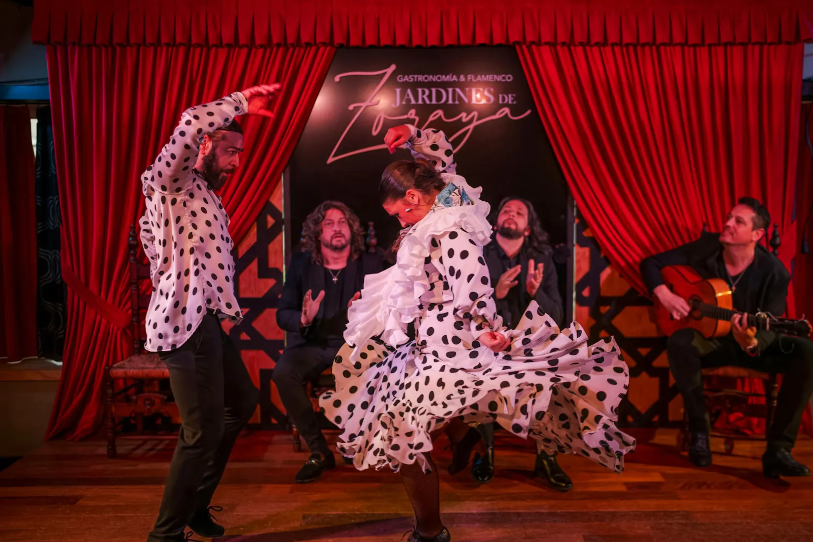 Flamenco dancers performing at Tablao Jardines de Zoraya with musicians in the background.