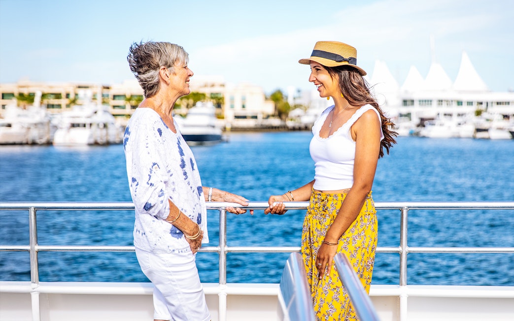 People chatting on a sightseeing cruise, Gold Coast marina in the background.