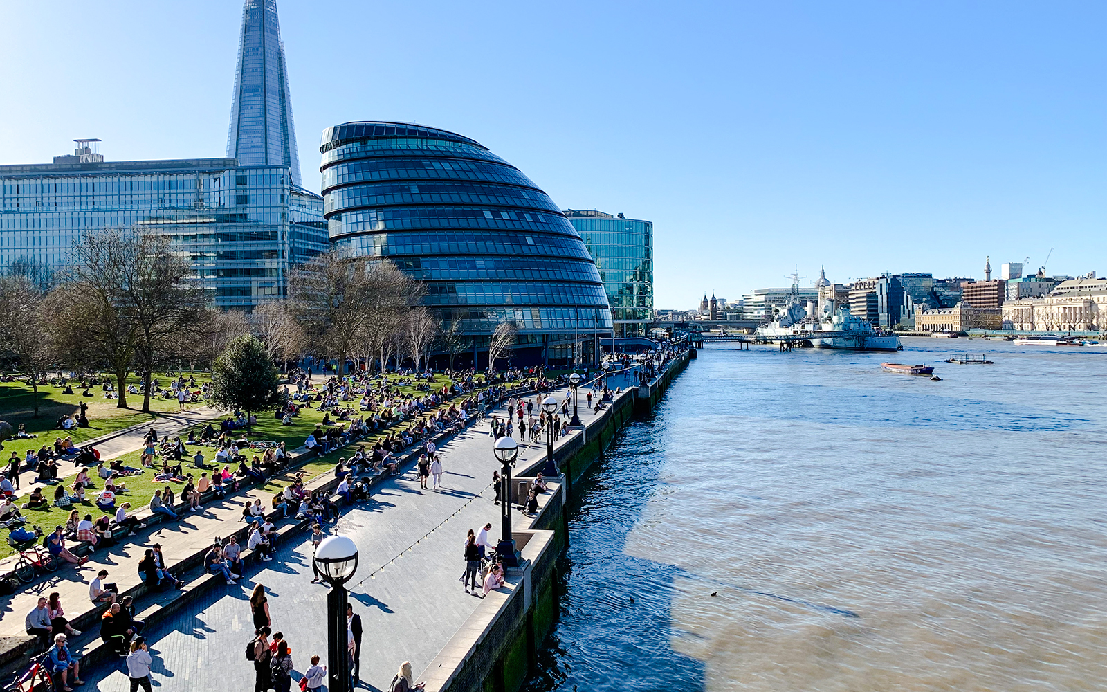 People relaxing at Potters Fields Park with City Hall and The Shard in the background, London.