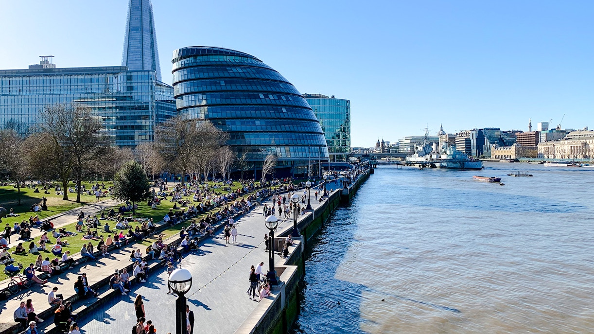 People relaxing at Potters Fields Park with City Hall and The Shard in the background, London.