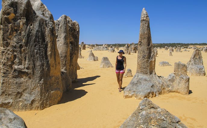 Person walking among limestone formations in Pinnacles Desert, Western Australia.