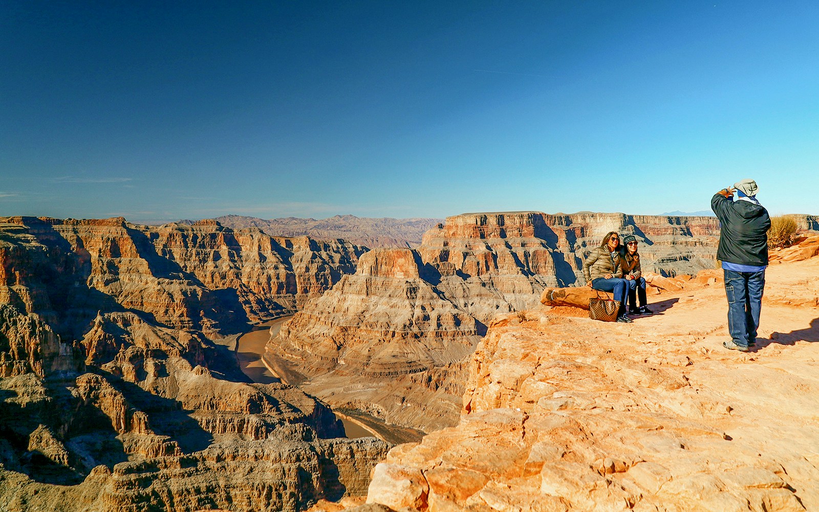 Grand Canyon rim with tourists from airplane tour, helicopter floor landing, and pontoon ride.