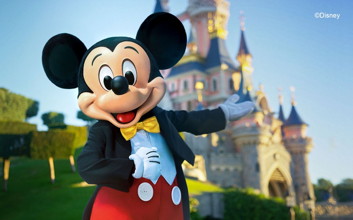 Mickey Mouse in front of Sleeping Beauty Castle at Disneyland Paris.