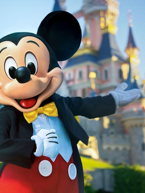 Mickey Mouse in front of Sleeping Beauty Castle at Disneyland Paris.