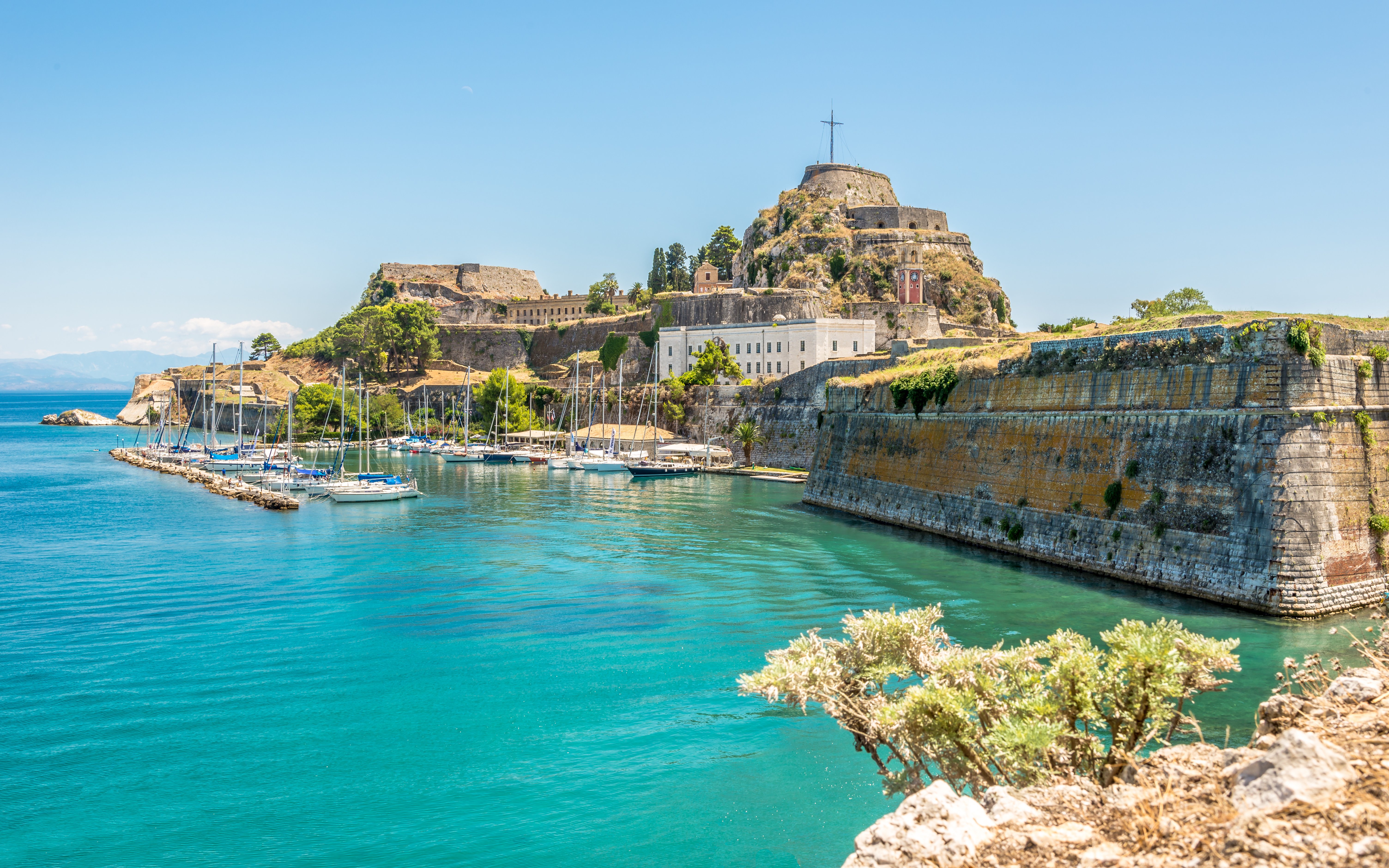 The Old Fortress of Corfu with yachts docked in the surrounding blue waters.