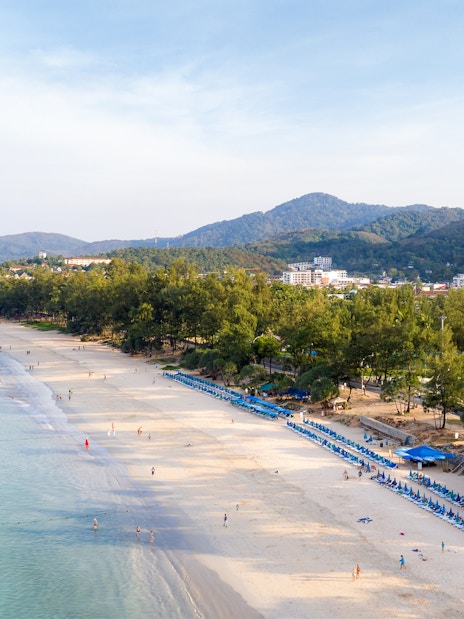 Aerial view of Patong Beach with sun loungers and surrounding hills, Phuket Discovery Tour.