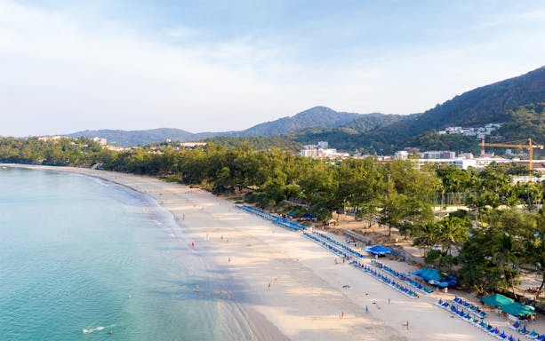 Aerial view of Patong Beach with sun loungers and surrounding hills, Phuket Discovery Tour.