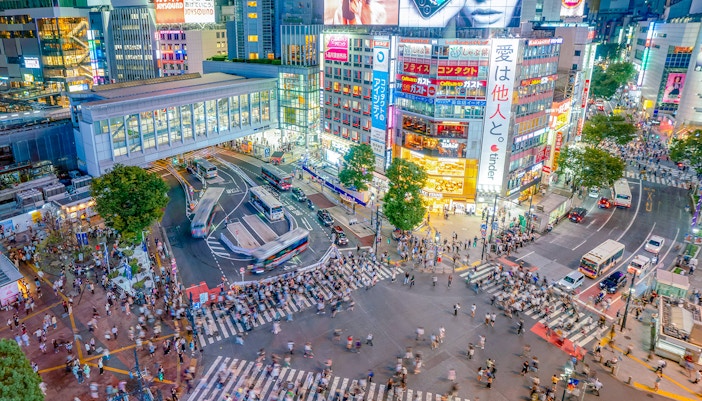 Shibuya Crossing view from Shibuya Sky Deck, Tokyo, with bustling crowds and illuminated buildings.