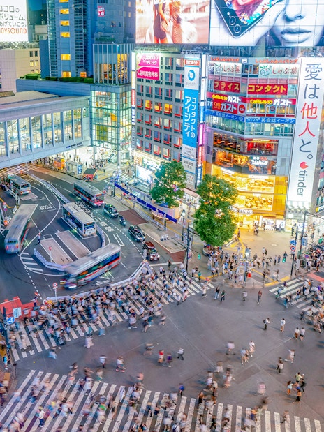 Shibuya Crossing view from Shibuya Sky Deck, Tokyo, with bustling crowds and illuminated buildings.