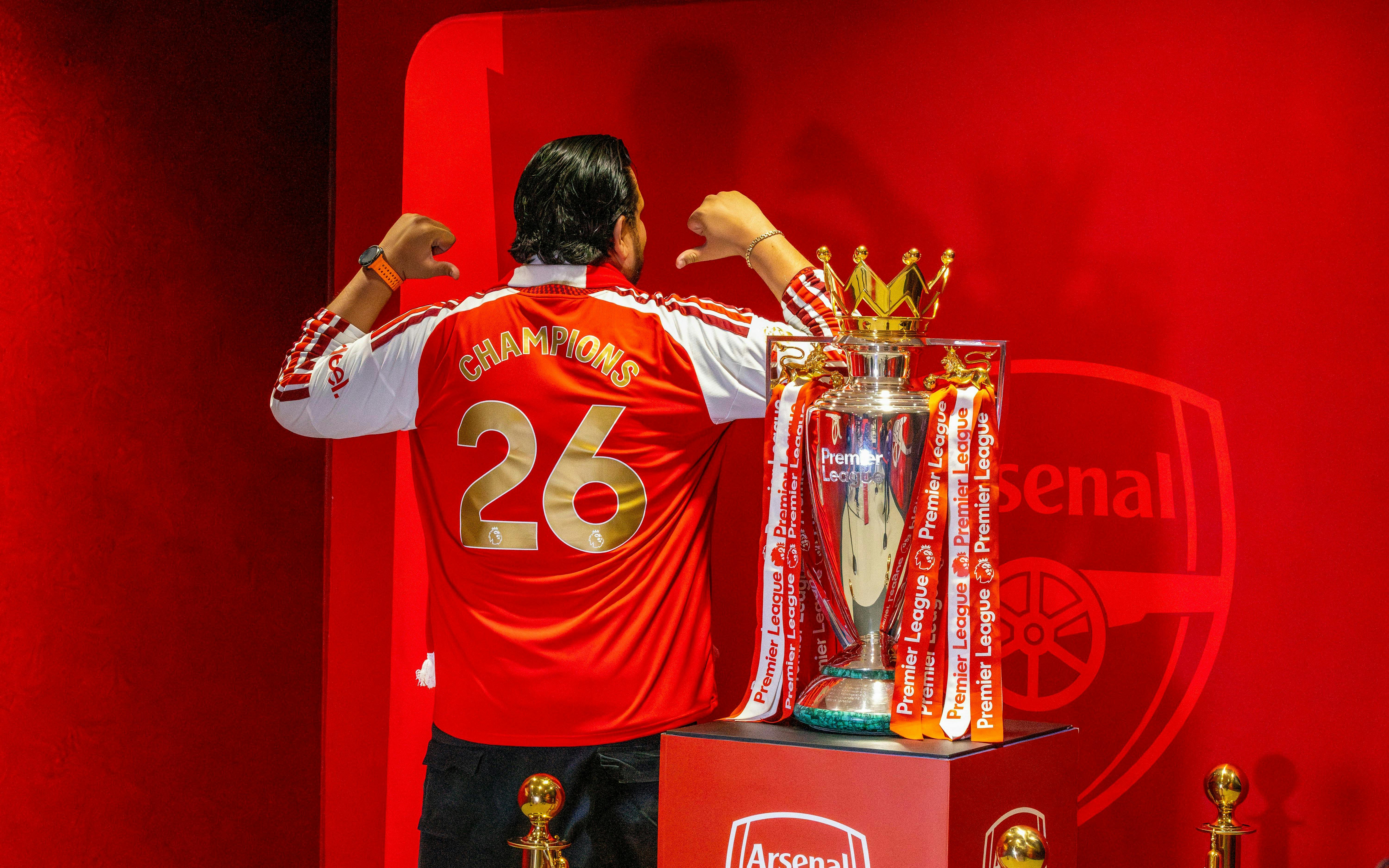 Premier League Trophy 2026 at The Emirates with fan in Champions jersey.