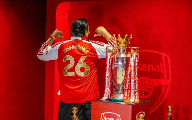 Premier League Trophy 2026 at The Emirates with fan in Champions jersey.