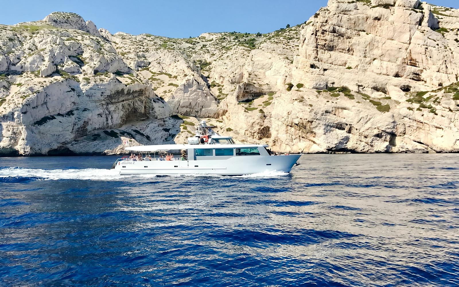 Boat cruising along rocky coastline during Monaco boat tour.