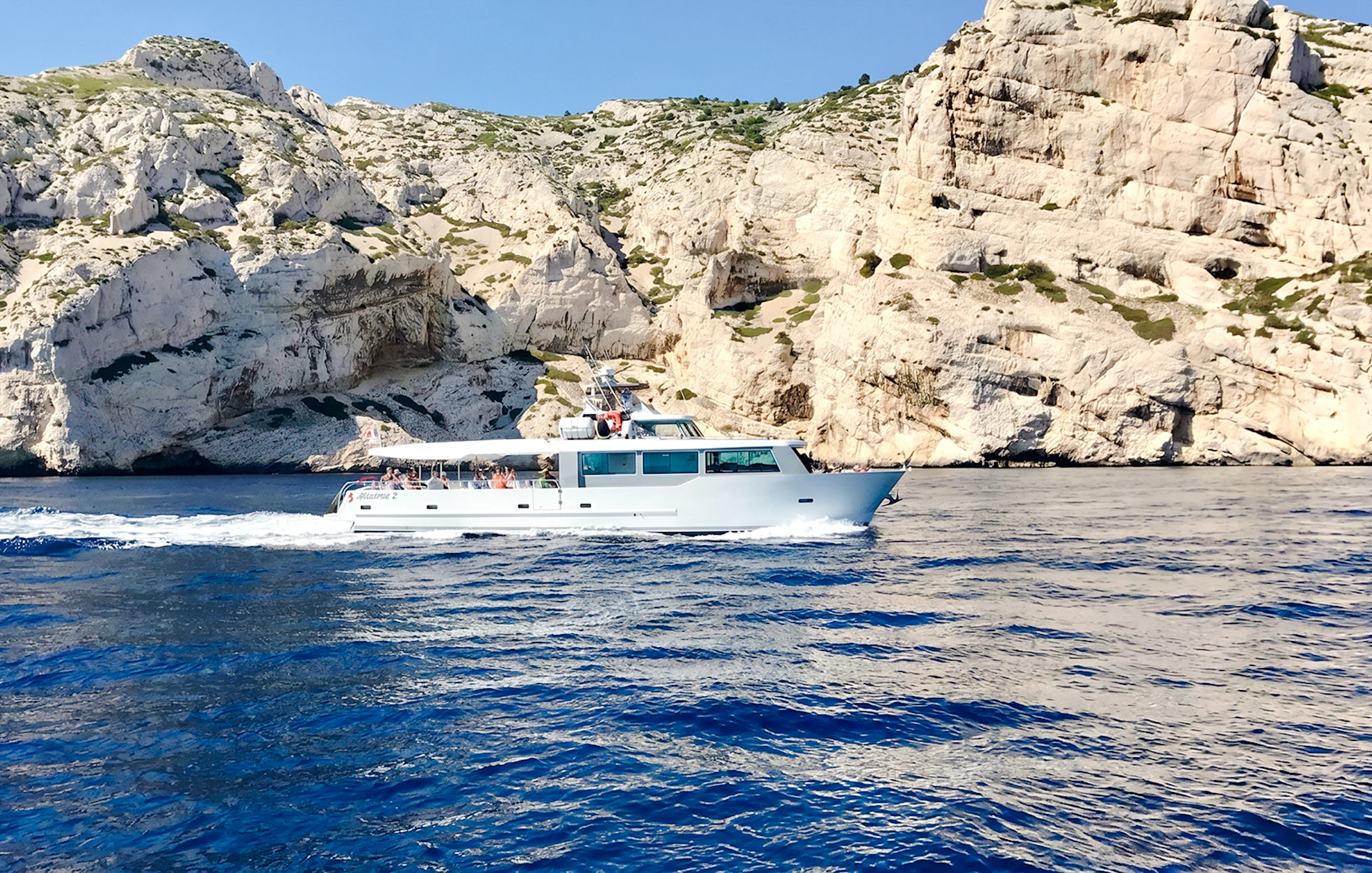 Boat cruising along rocky coastline during Monaco boat tour.