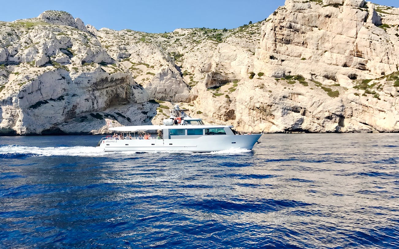 Boat cruising along rocky coastline during Monaco boat tour.