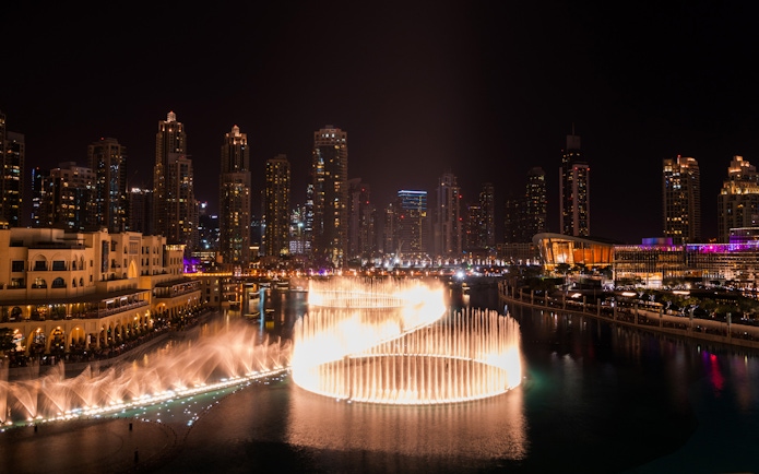 Dubai Fountain show at night with city skyline, viewed from Big Bus Dubai Night Tour.