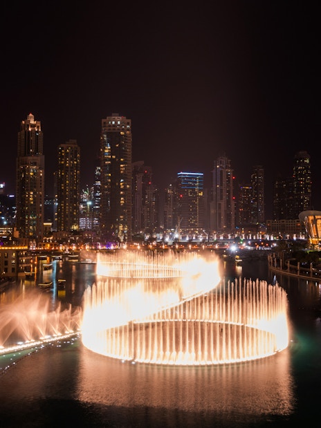 Dubai Fountain show at night with city skyline, viewed from Big Bus Dubai Night Tour.
