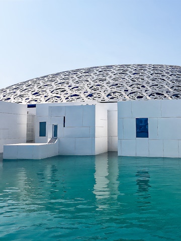 Louvre Abu Dhabi's dome and modern architecture over water.