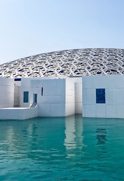 Louvre Abu Dhabi's dome and modern architecture over water.