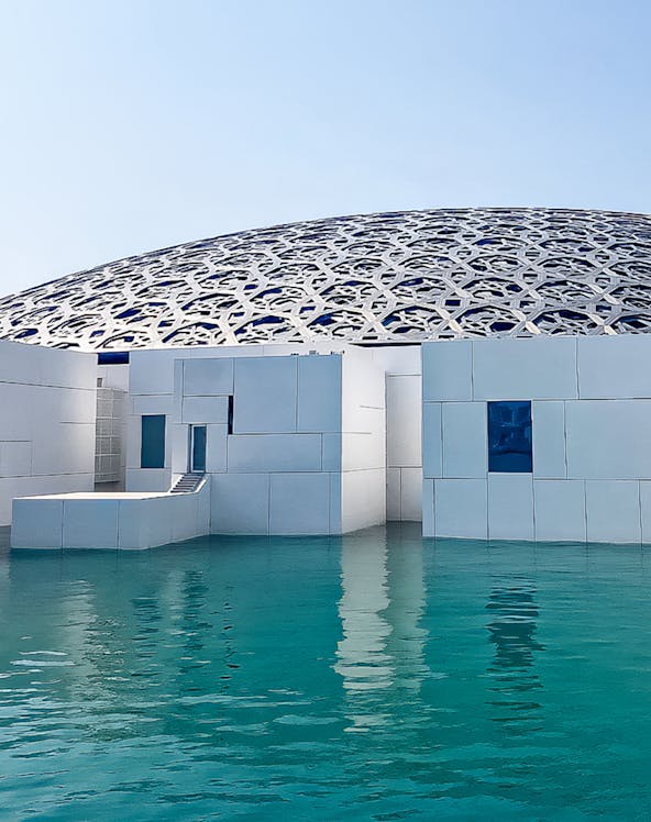 Louvre Abu Dhabi's dome and modern architecture over water.