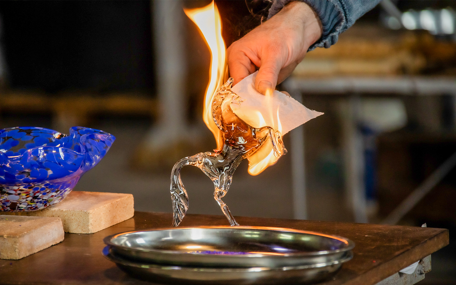 Glassblowing demonstration in Murano, Venice, with a flaming glass horse sculpture.