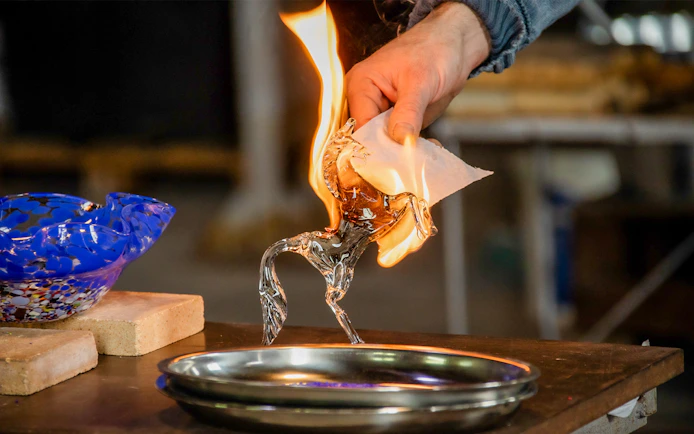 Glassblowing demonstration in Murano, Venice, with a flaming glass horse sculpture.